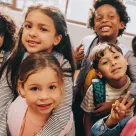 A group of 6-year-old children in a school classroom.