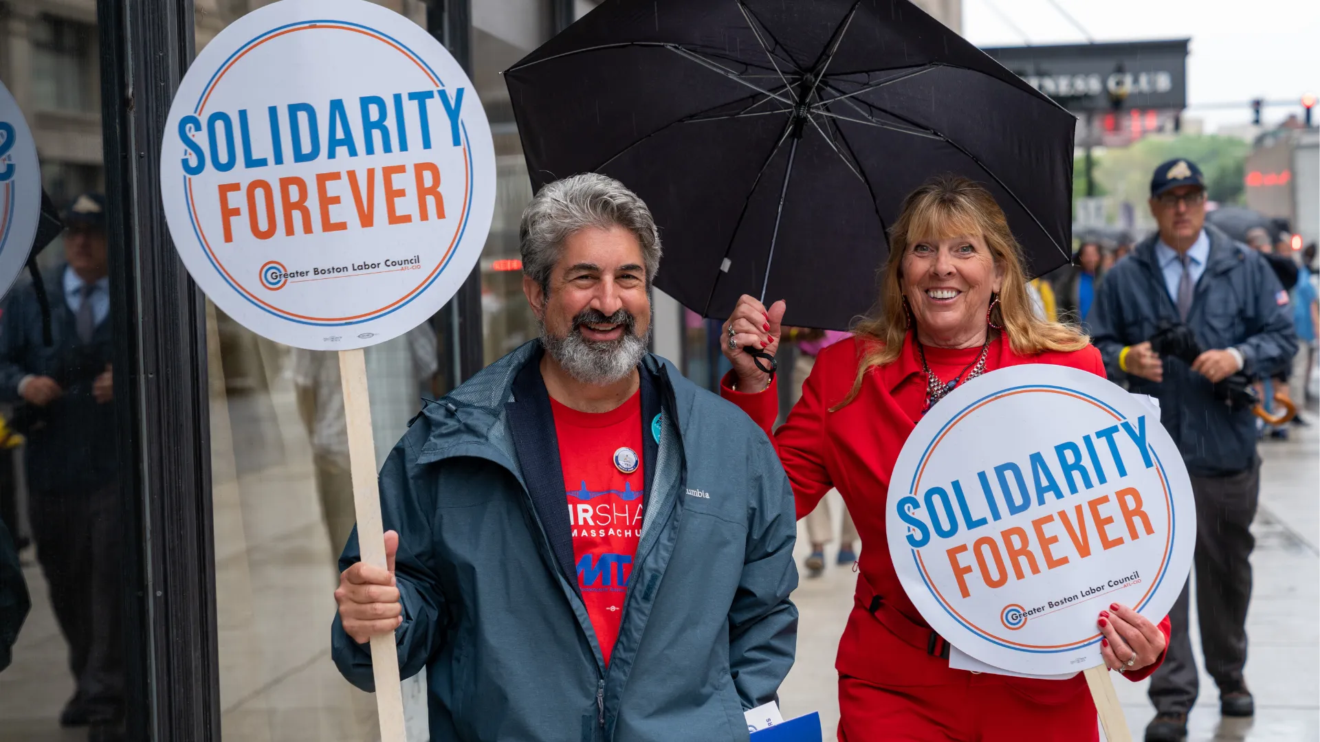 Max Page and Deb McCarthy at a Boston rally holding “Solidarity Forever” signs.
