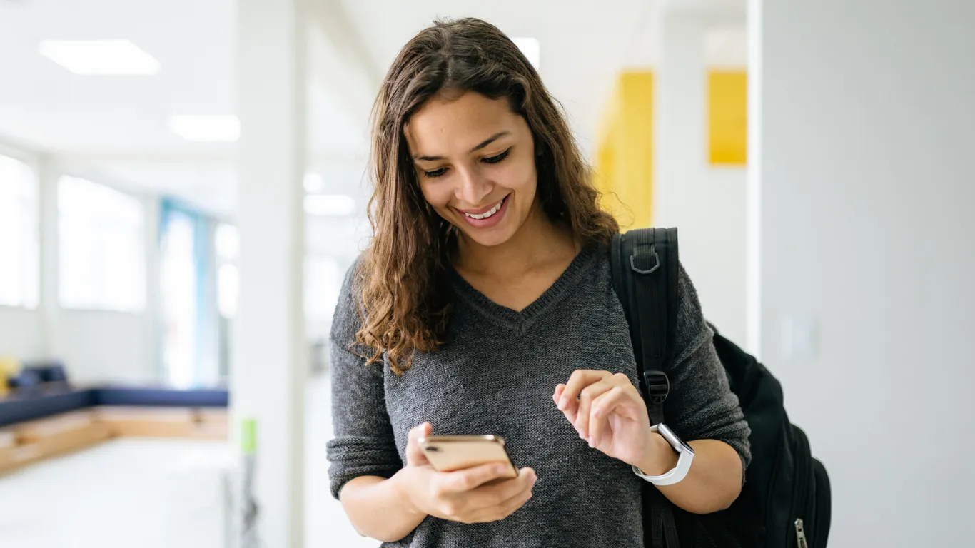 Educator woman looking at her mobile phone with a happy expression.